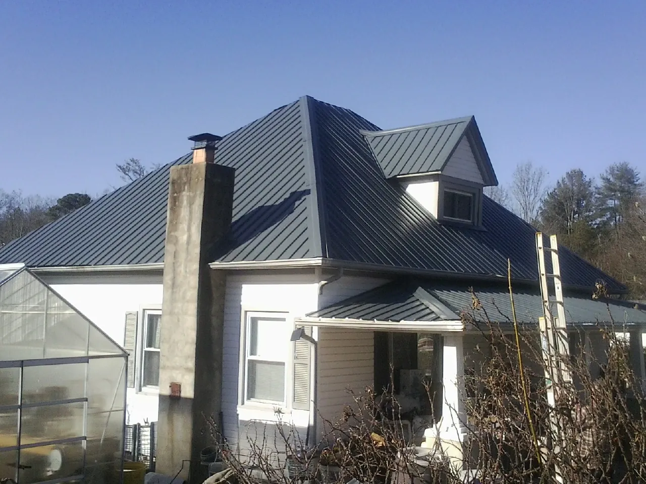 Dark blue standing seam metal roof on a white farmhouse with dormer — Slate & Tile Roof Repair by Roofing Brothers in Lemont