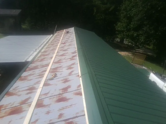 Old rusted panels beside newly installed green metal roofing — Wind Damage Roof Repair by Roofing Brothers in Lemont