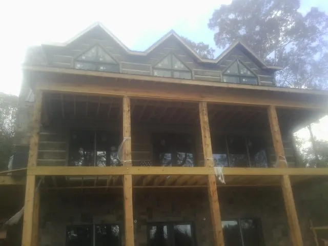 Dormers and porch framing on a large log home under construction — Roof Coating work by our crew in Lemont