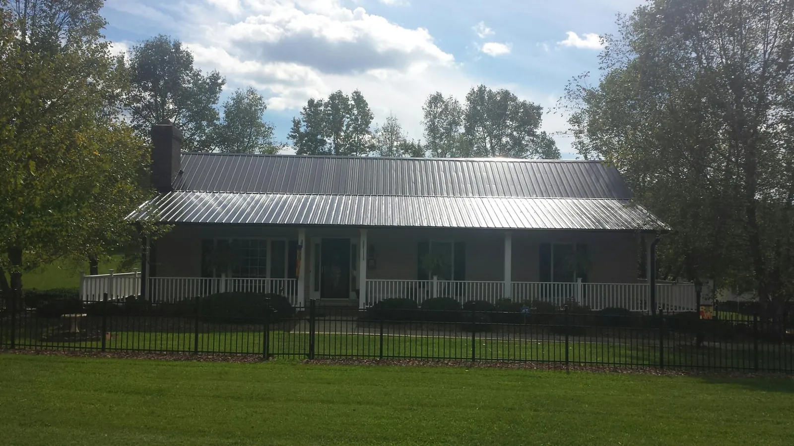 Gray metal roof on a brick ranch with a full width front porch — Gutter Guard Installation work by our crew in Lemont