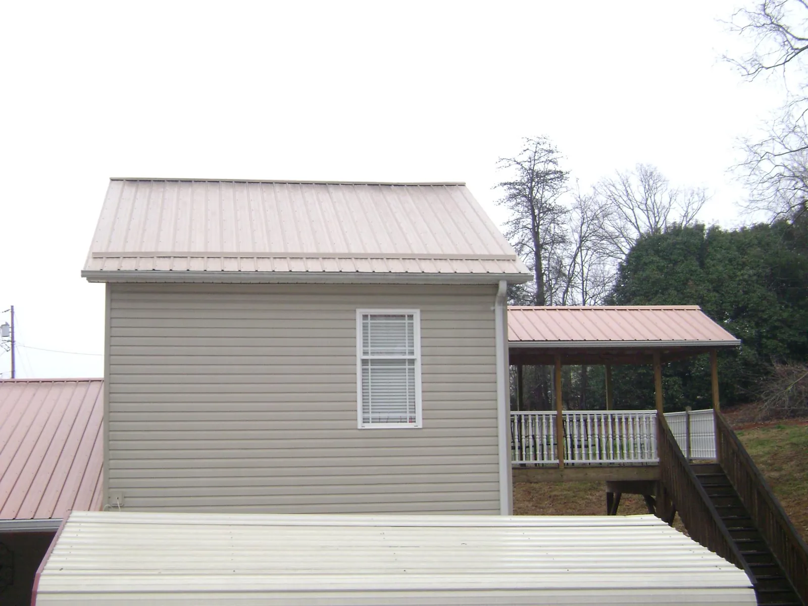 Tan metal roofs on a two story addition and attached porch, from a Roof Replacement job in Lemont