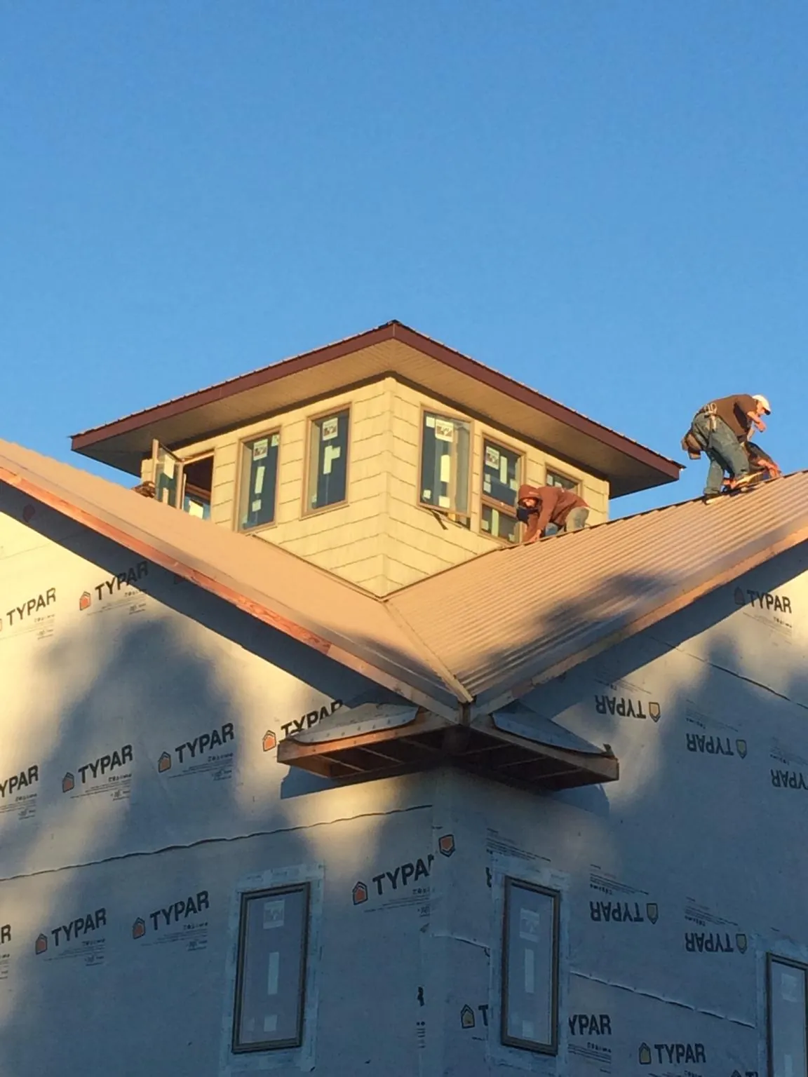 Roofers working around a rooftop cupola on a new metal roof at sunset — Roof Waterproofing in Lemont by Roofing Brothers